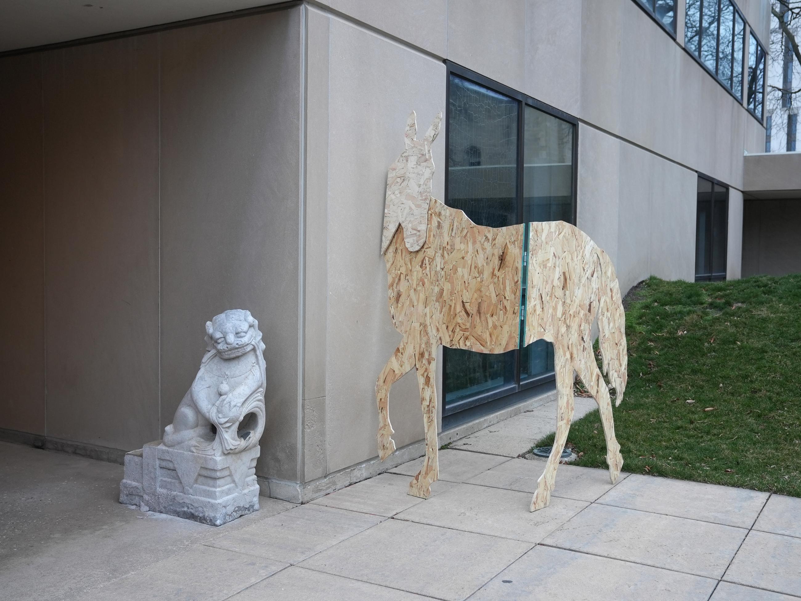 life-size silhouettes of horses made from plywood, hinged, outside of building with stone dragon