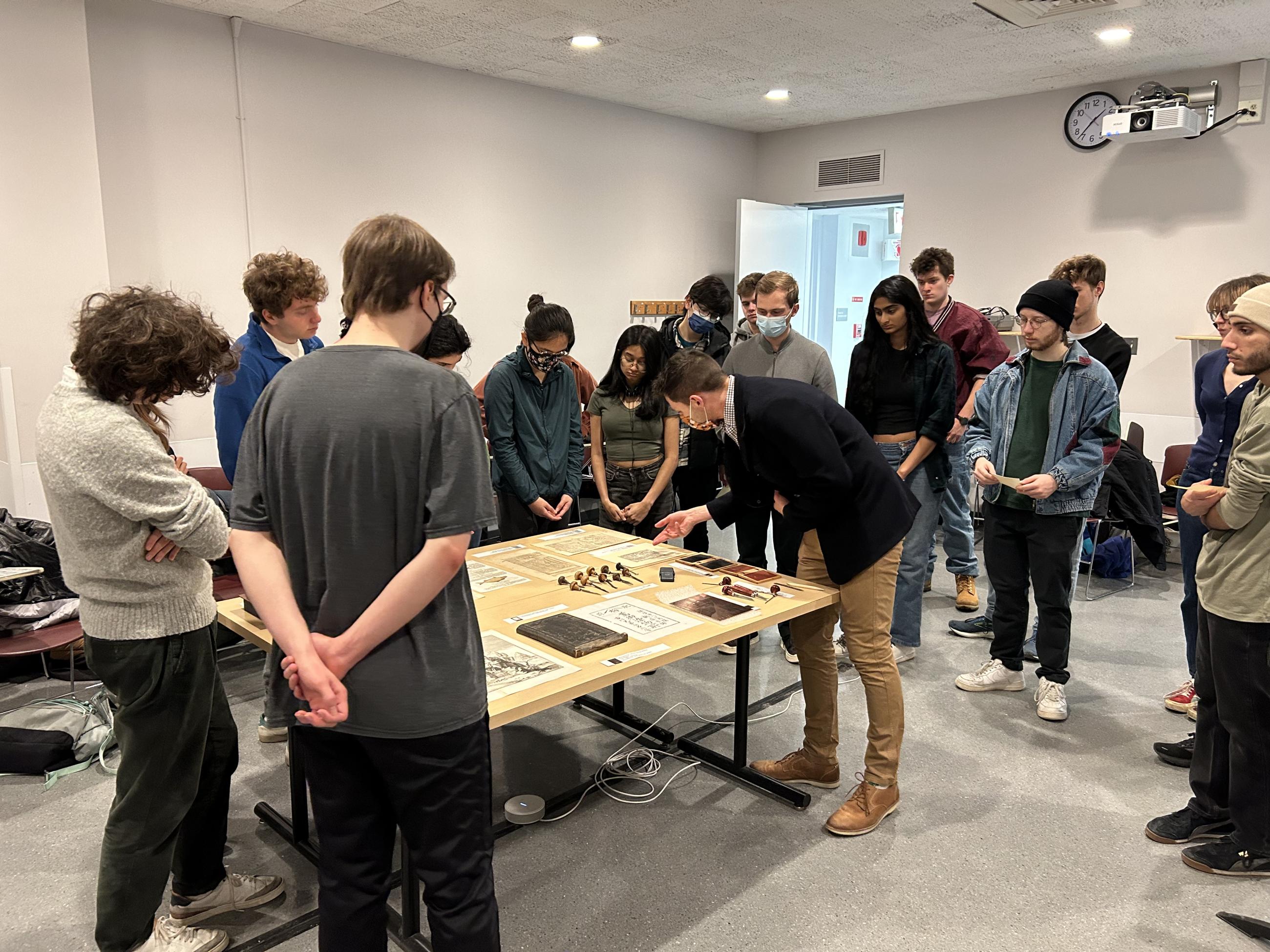 Large group of students examining prints on a table