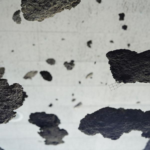 Patches of gray debris hung from the ceiling with invisible fishing wire, suggesting the aftermath of a disaster