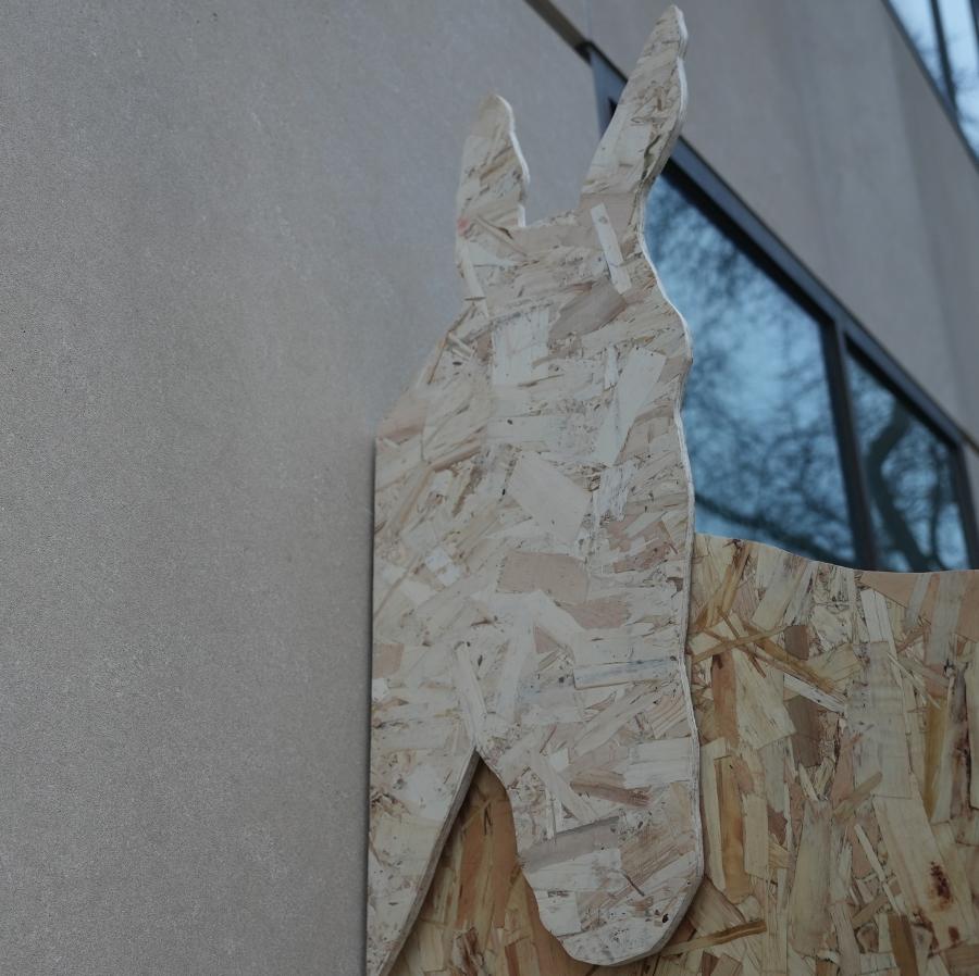 Detail of a plywood horse head against a limestone building exterior