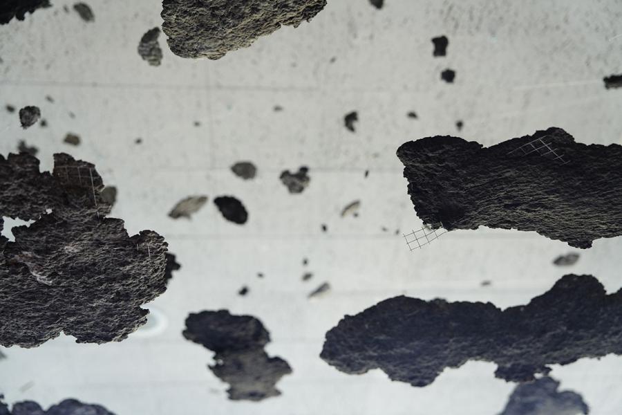 Patches of gray debris hung from the ceiling with invisible fishing wire, suggesting the aftermath of a disaster