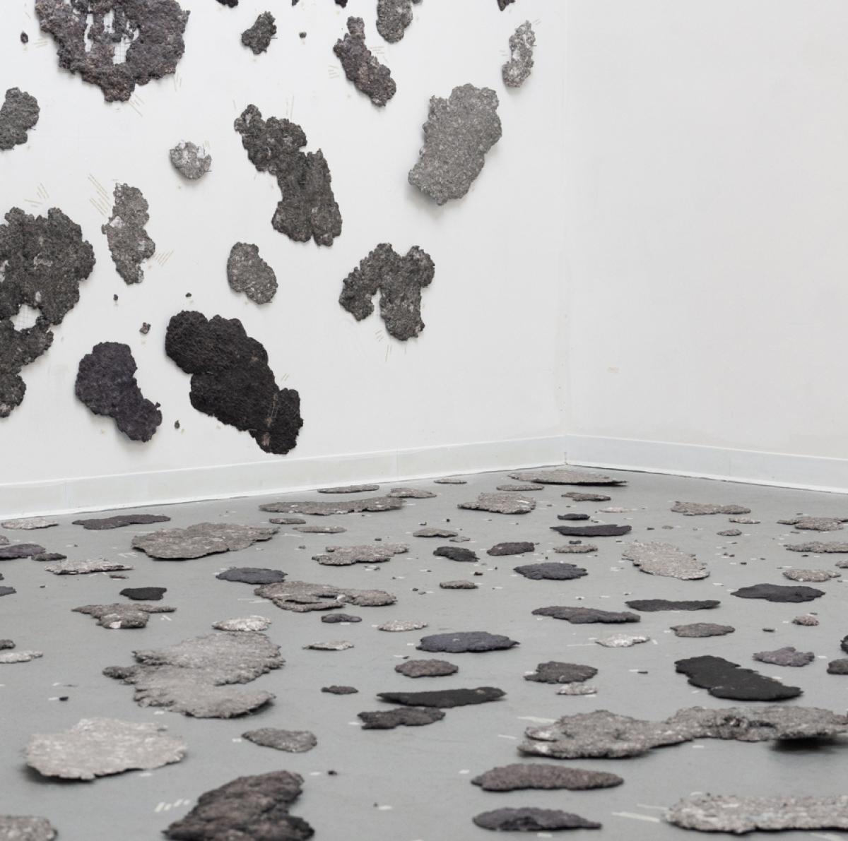 Patches of gray debris randomly fill the wall and floor, suggesting the aftermath of a disaster