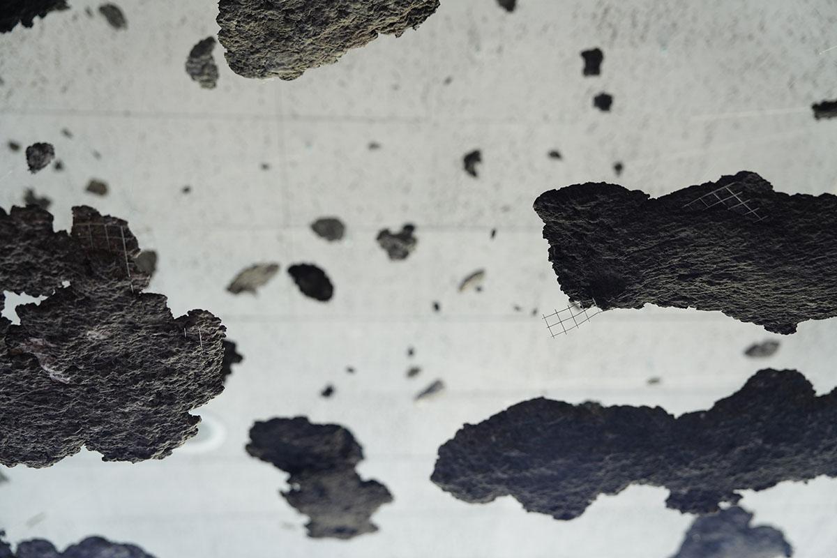 Patches of gray debris hung from the ceiling with invisible fishing wire, suggesting the aftermath of a disaster